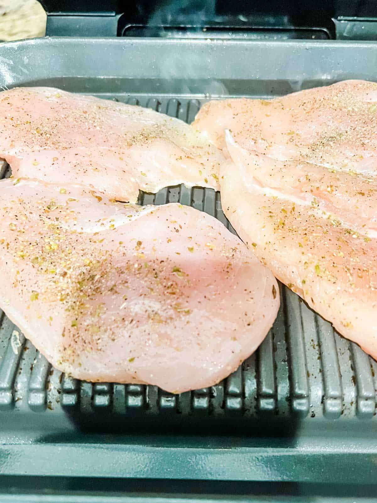 Photo of seasoned raw chicken that has just been placed on a Ninja Foodi Grill.