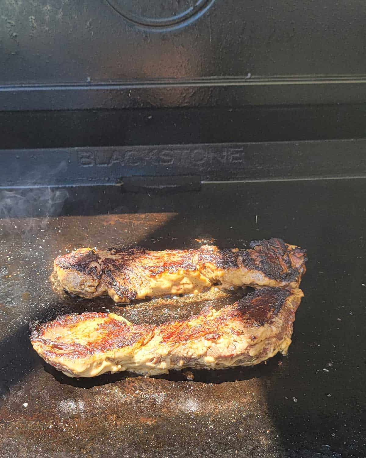 Photo of hanger steaks cooking on a blackstone griddle.