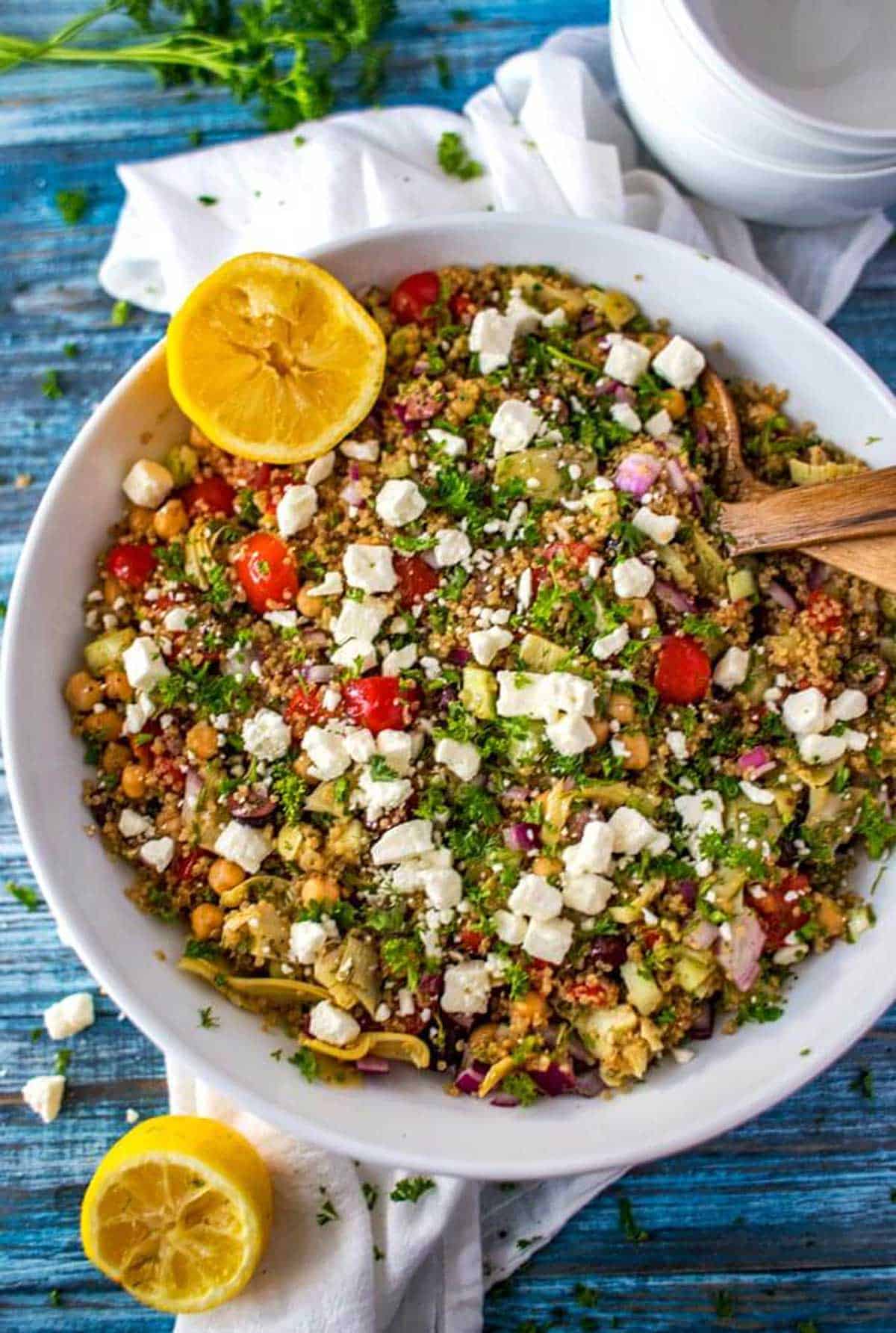 Close up overhead photo of a Mediterranean quinoa salad in a white bowl.