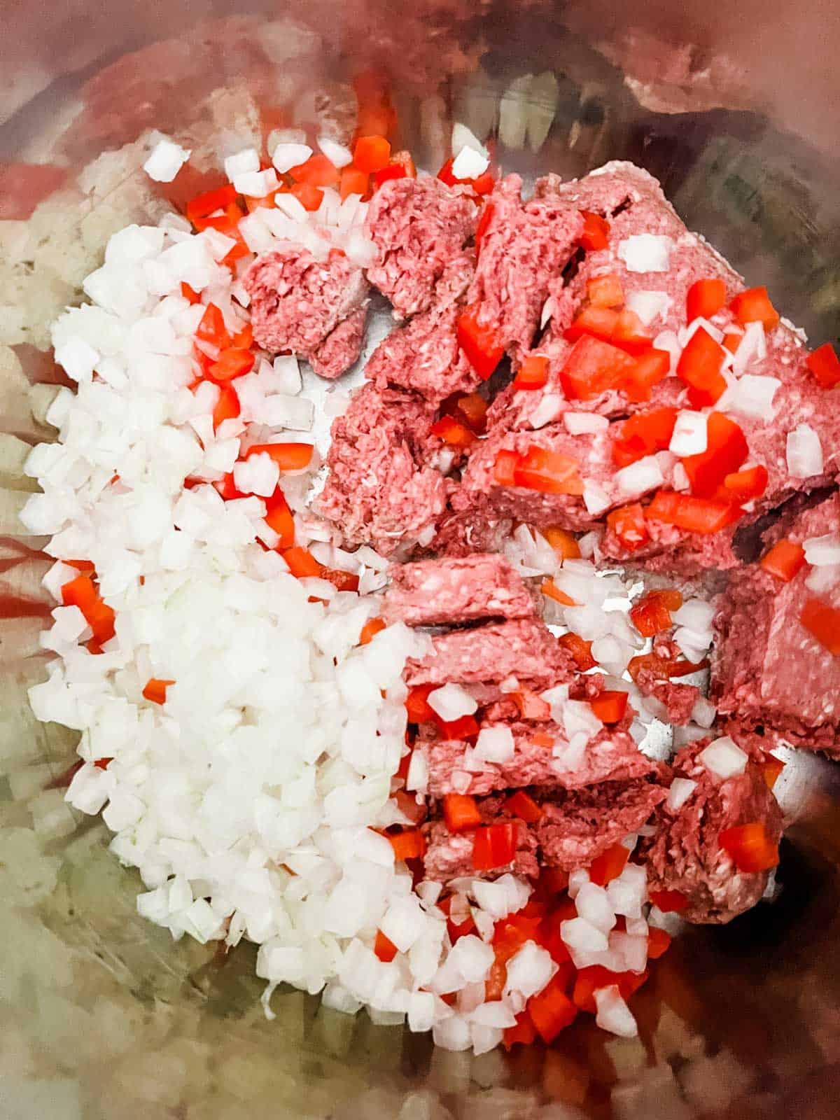 Overhead photo of ground beef, onion, and red pepper in an Instant Pot.
