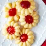 Close up square photo of thumbprint cookies with jam.