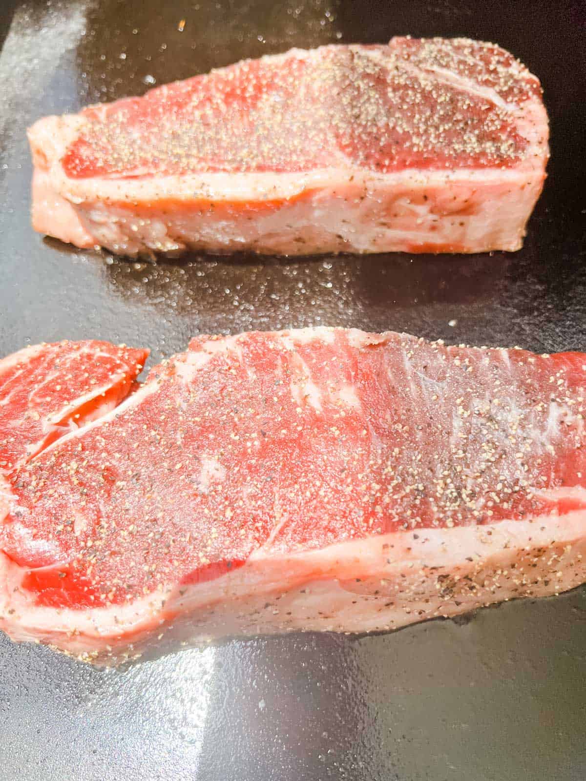 Photo of steaks cooking on a Blackstone griddle.