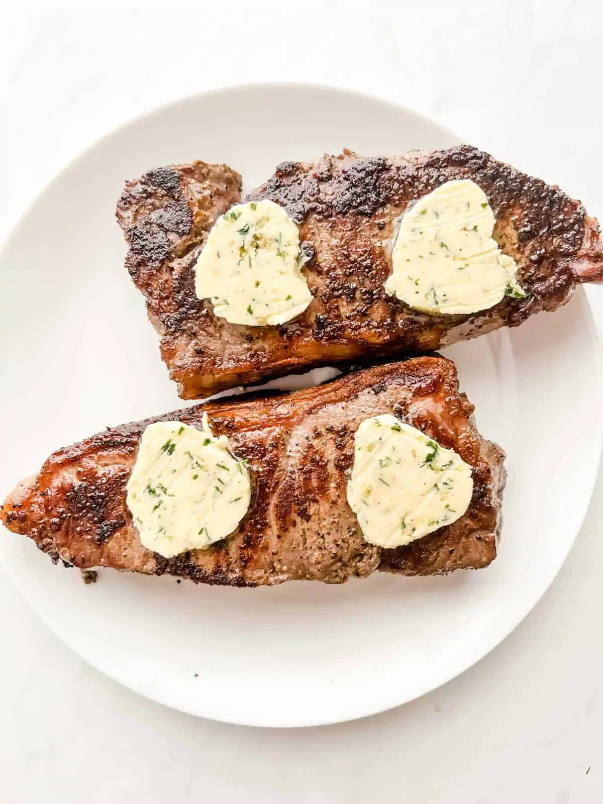 Photo of steaks that have been cooked and have just had compound butter put on top of them.
