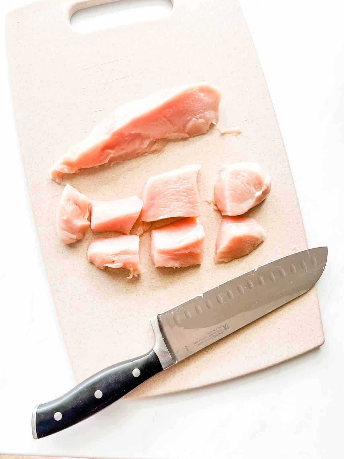 Photo of boneless skinless chicken breast being cut for chicken nuggets.