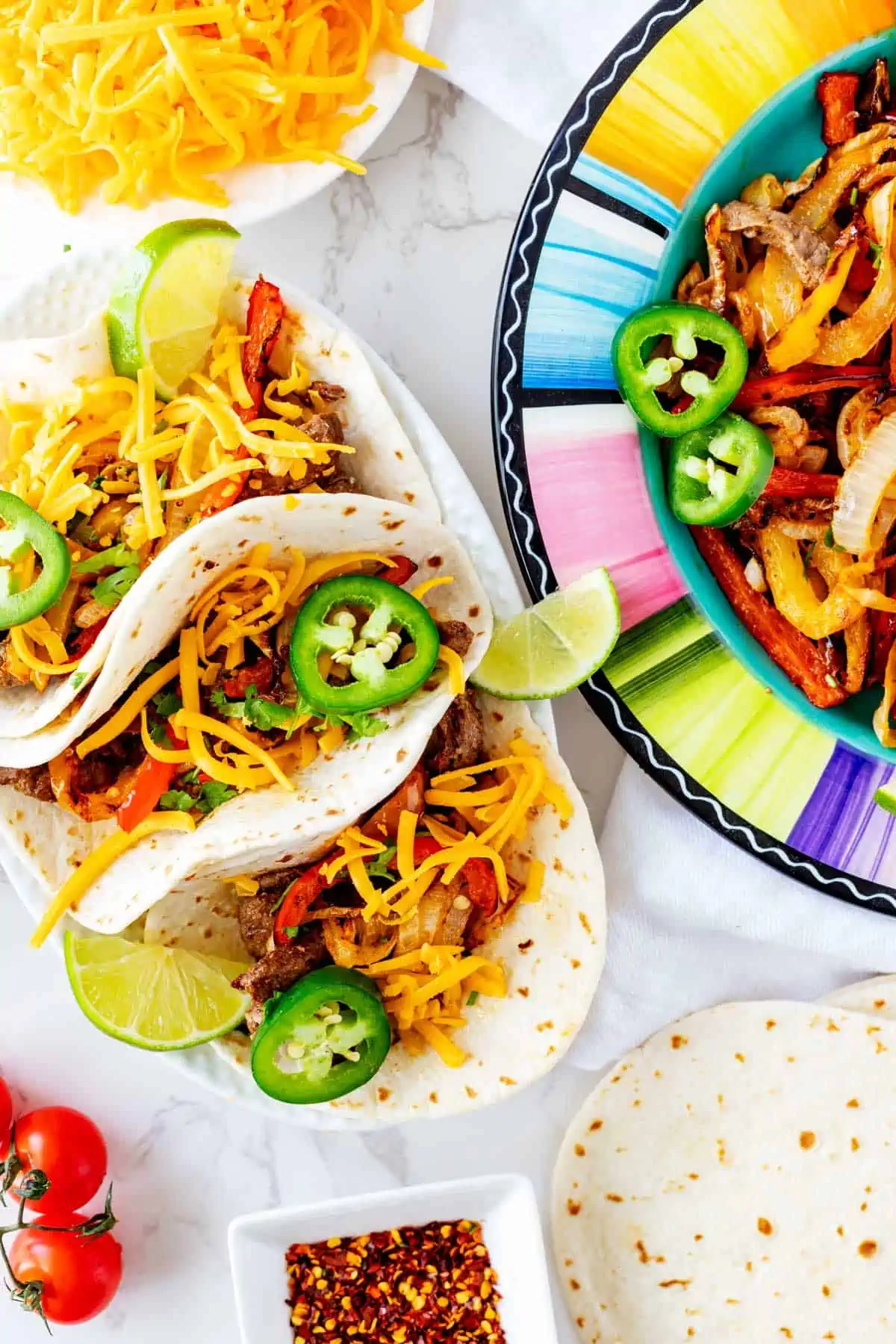 Overhead photo of air fryer fajitas on an oval platter with a bowl of fajita meat and vegetables beside it.
