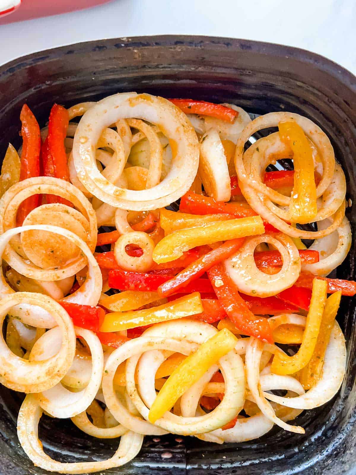 Photo of onions and peppers in and air fryer basket.