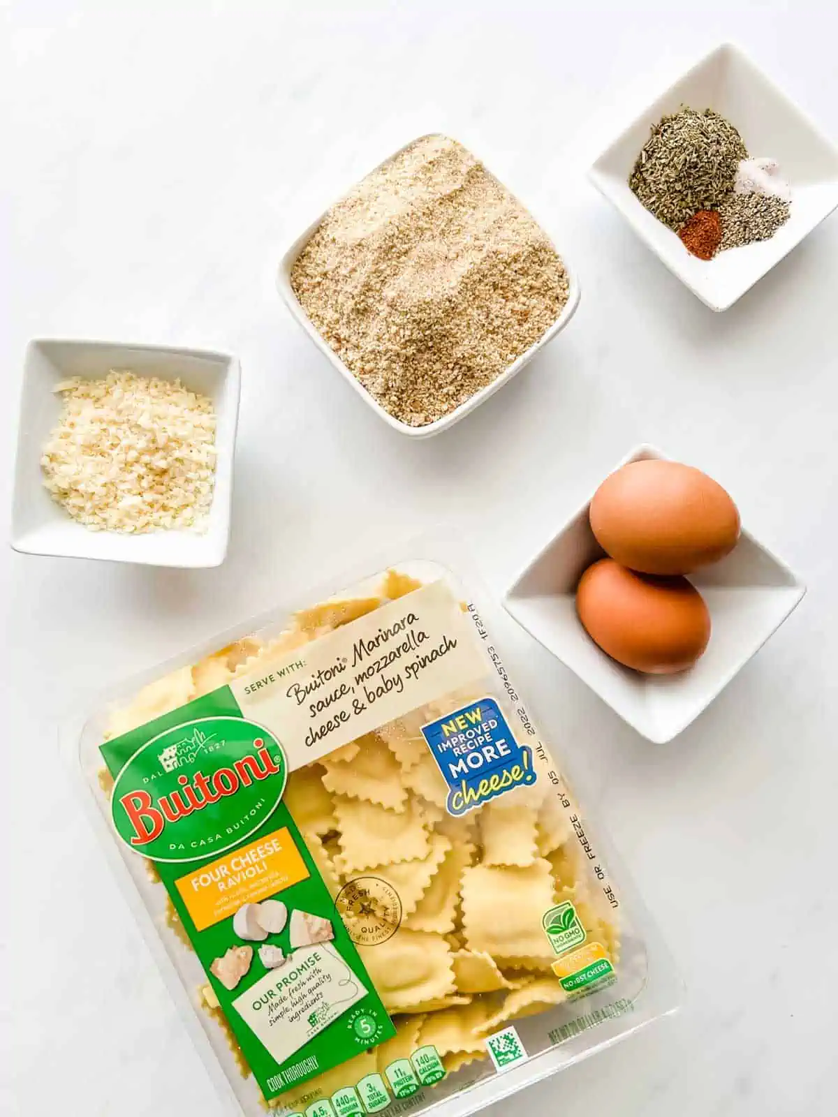 Overhead photo of refrigerated ravioli, eggs, cheese, breadcrumbs and seasonings in prep bowls.