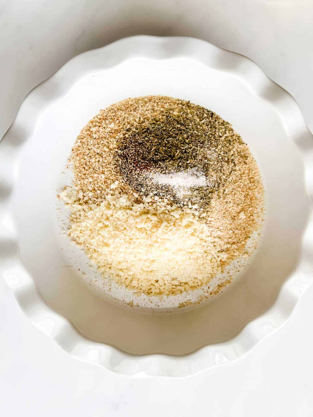 Photo of a pie plate with breadcrumbs, parmesan, and seasonings.
