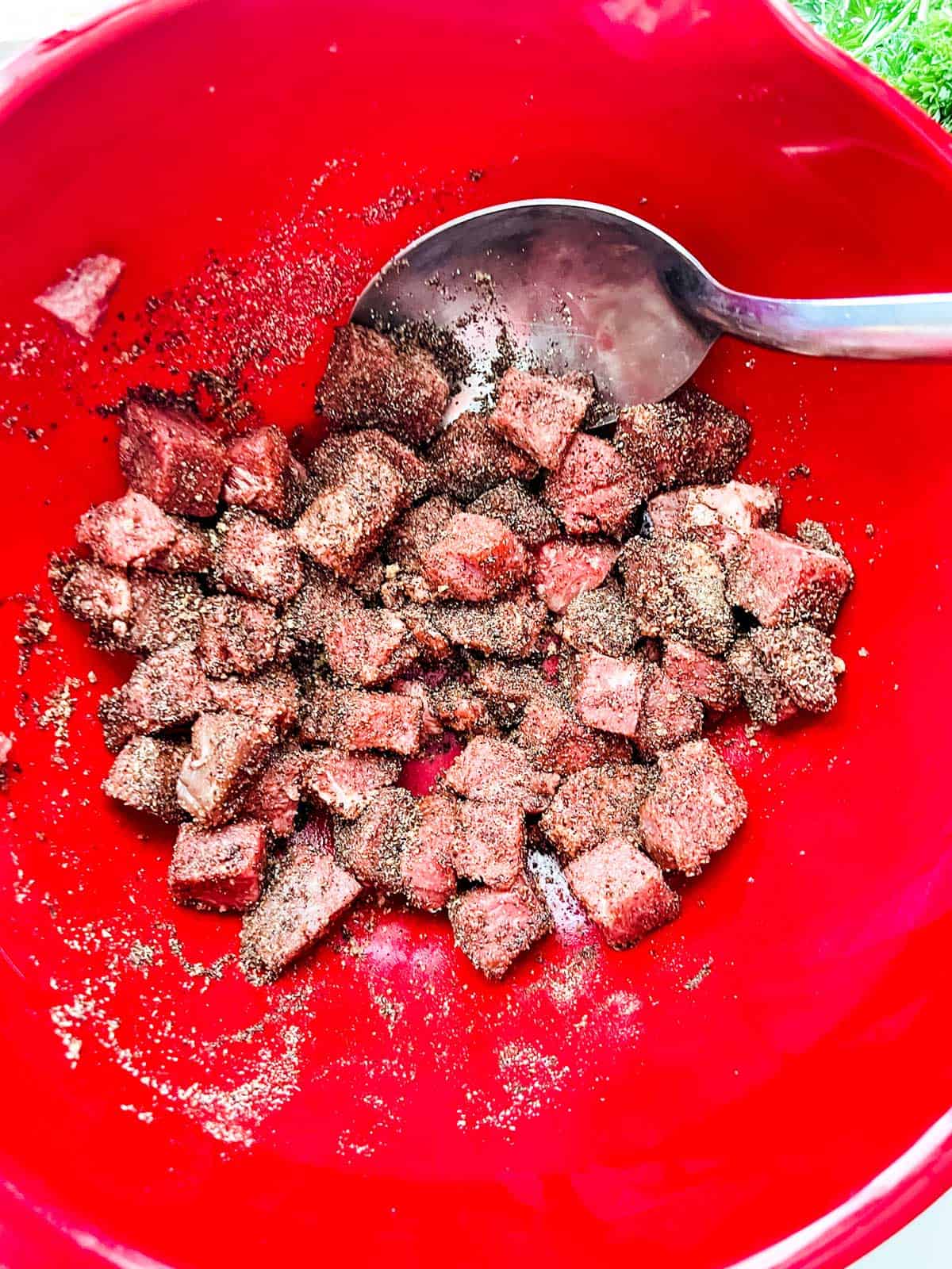 Photo of steak bites tossed with seasonings and oil.