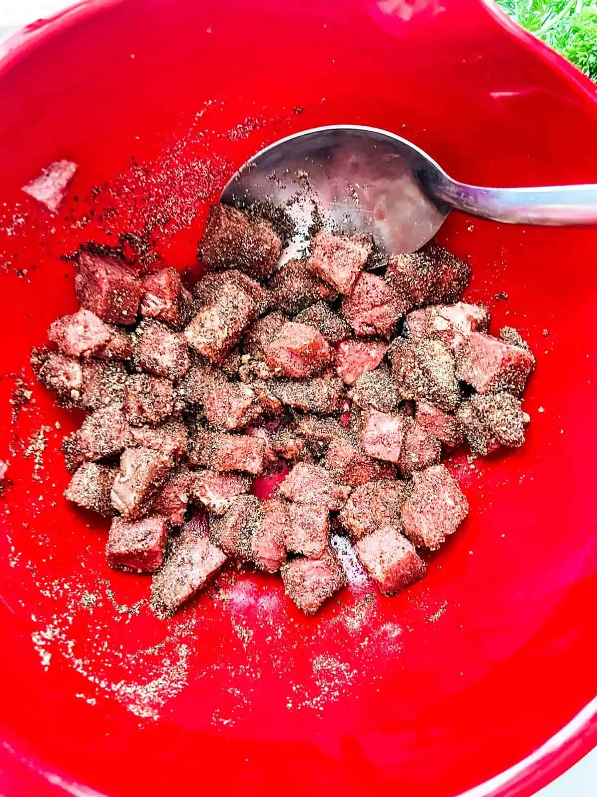 Photo of steak bites tossed with seasonings and oil.