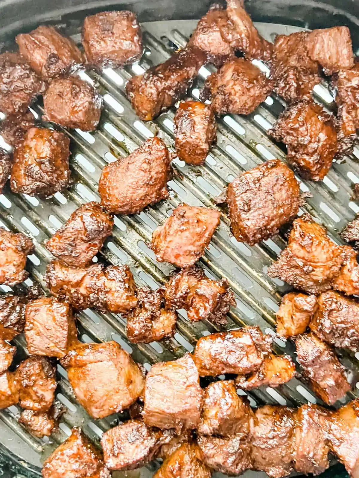 Photo of steak bites being cooked in a air fryer.