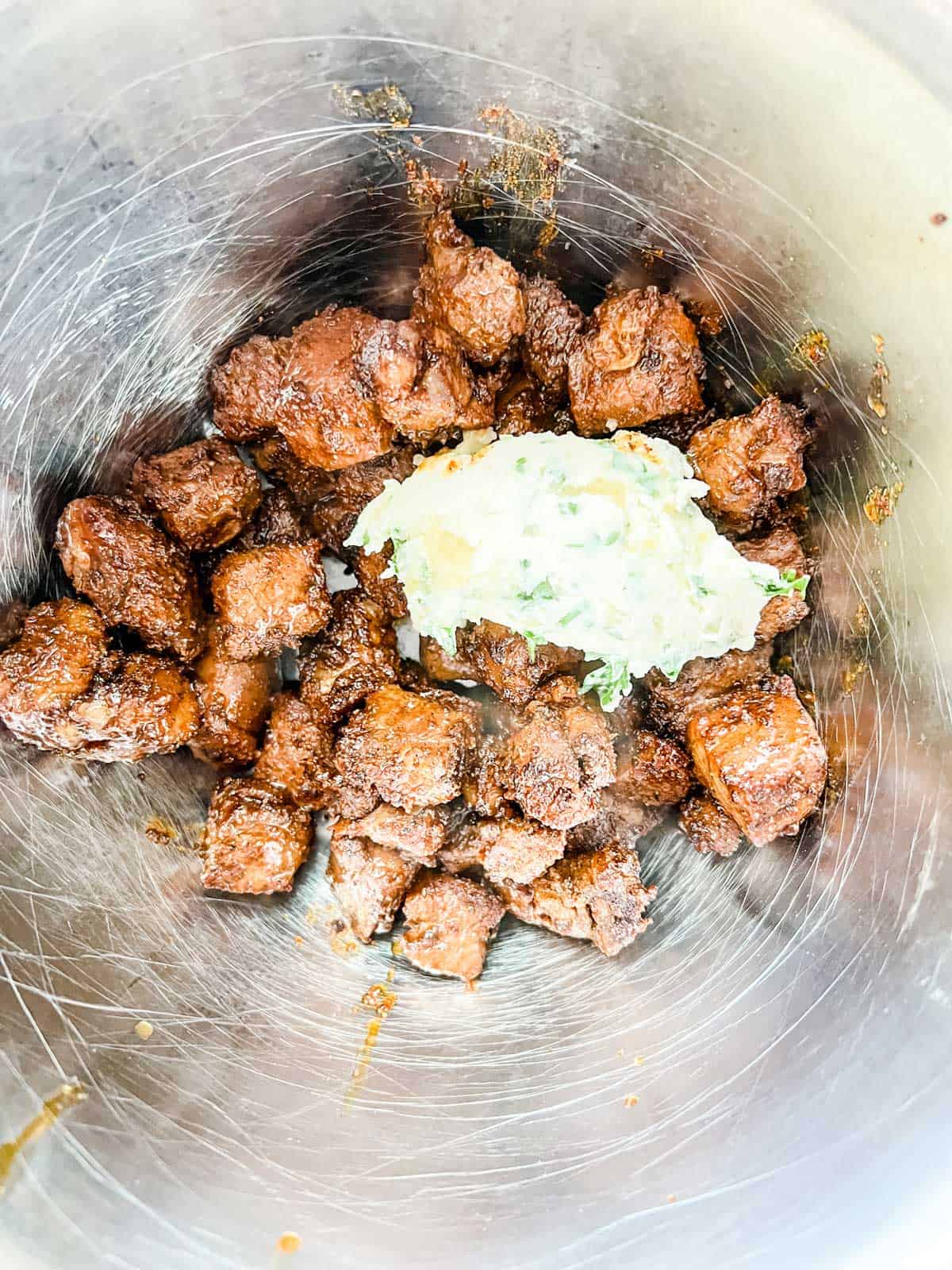 Photo of garlic butter over cooked steak bites.