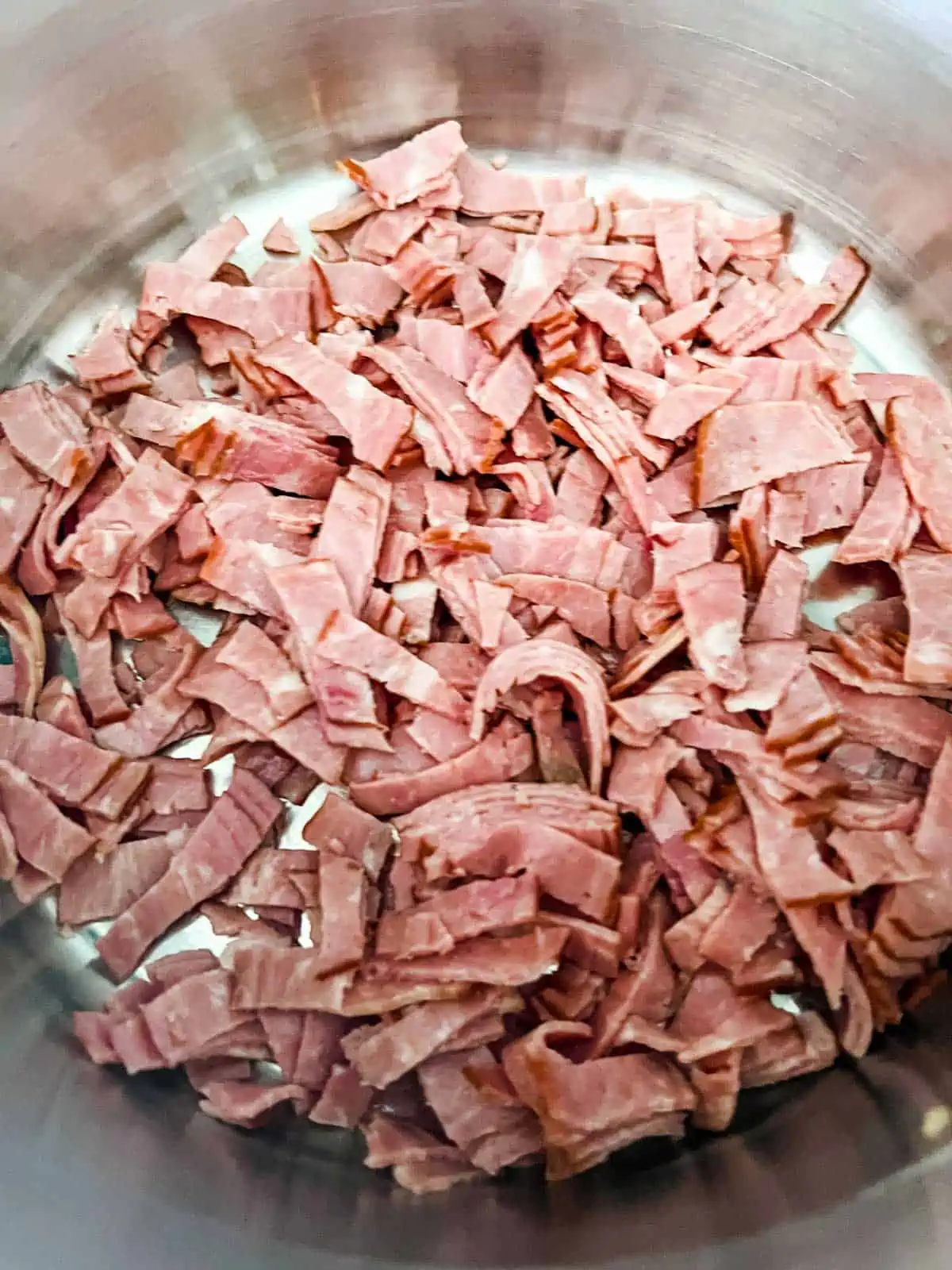 Photo of bacon cooking in a dutch oven.