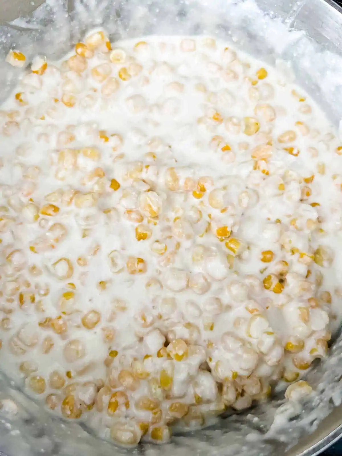 Photo of corn added to a cheesy cream sauce.