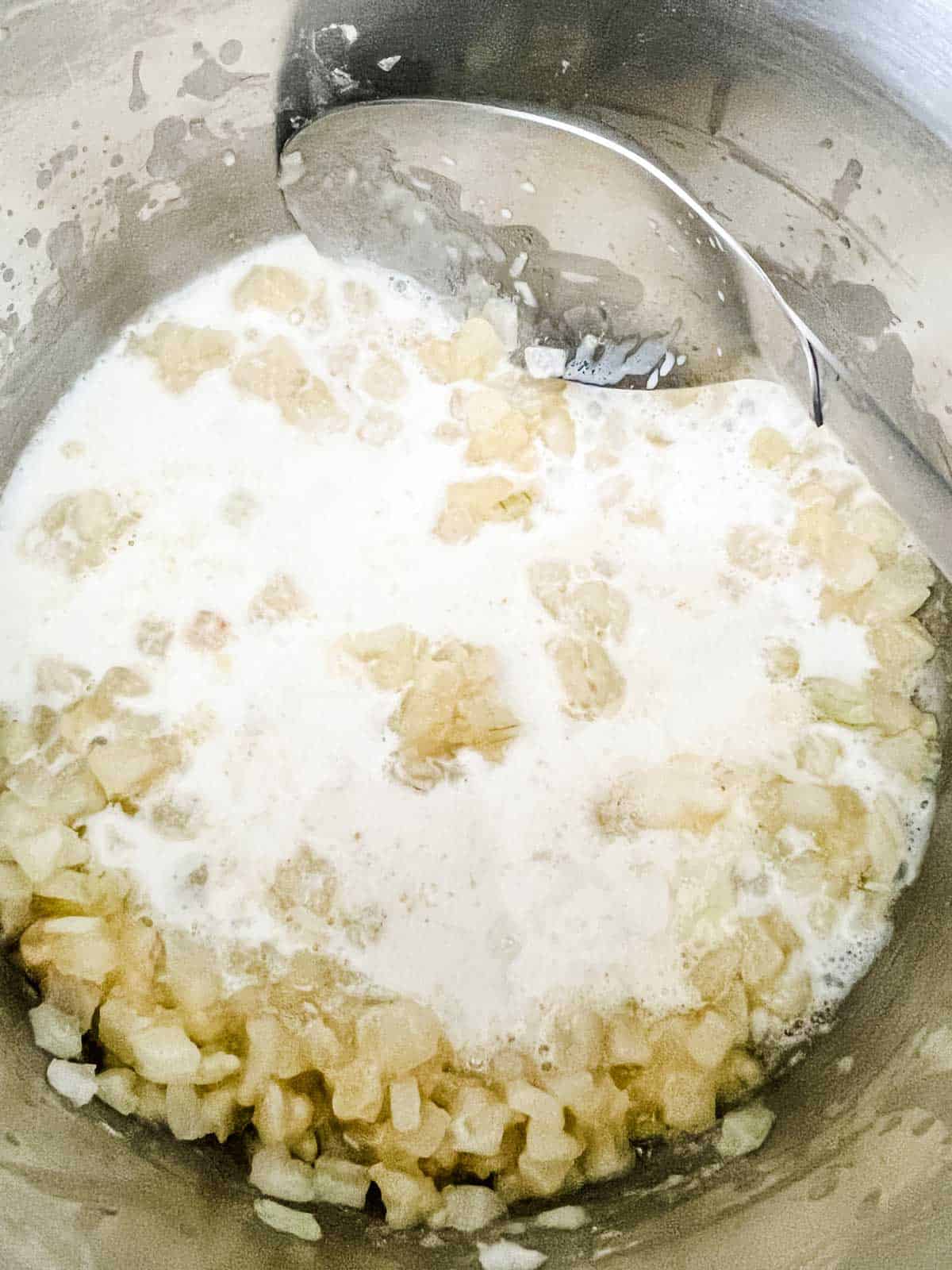 Photo of milked being added to butter, onion, and flour.