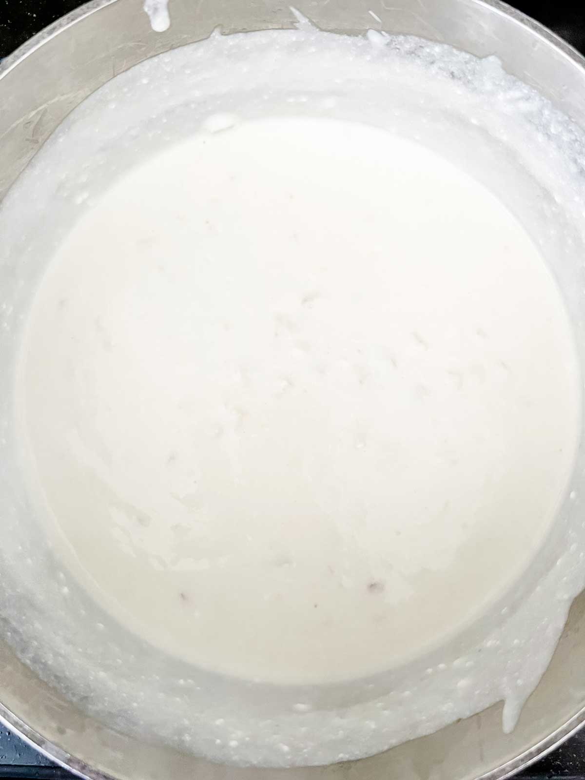 Photo of a cheesy cream sauce in a saucepan.