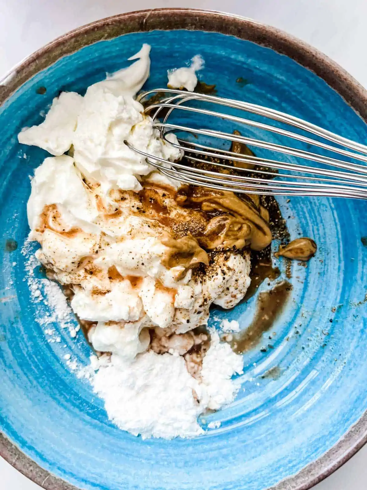 Greek yogurt, dijon, sweetener, and seasonings in a bowl.