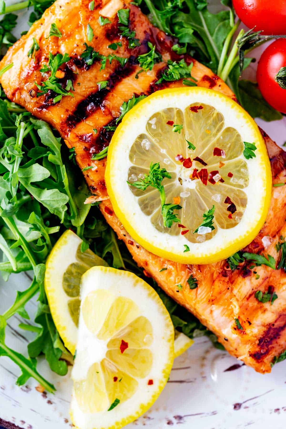 Close up photo of ninja foodi grill salmon garnished with lemon, parsley, and red pepper flakes.