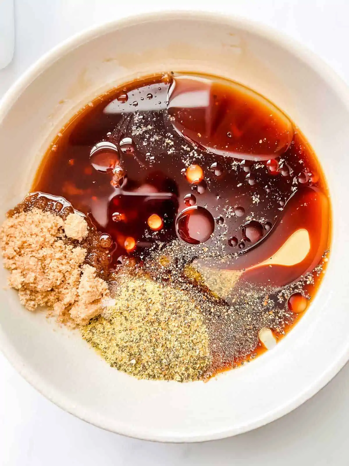 Photo of oil, soy sauce, brown sugar, and seasonings in a small bowl.
