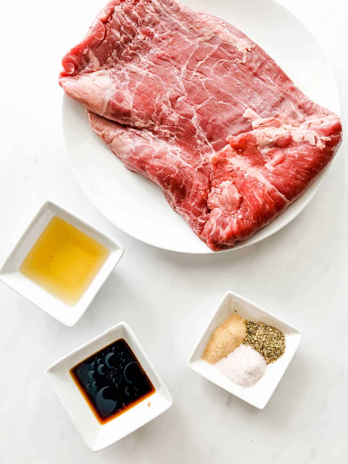 Photo of flank steak, oil, soy sauce, and seasonings in prep bowls.
