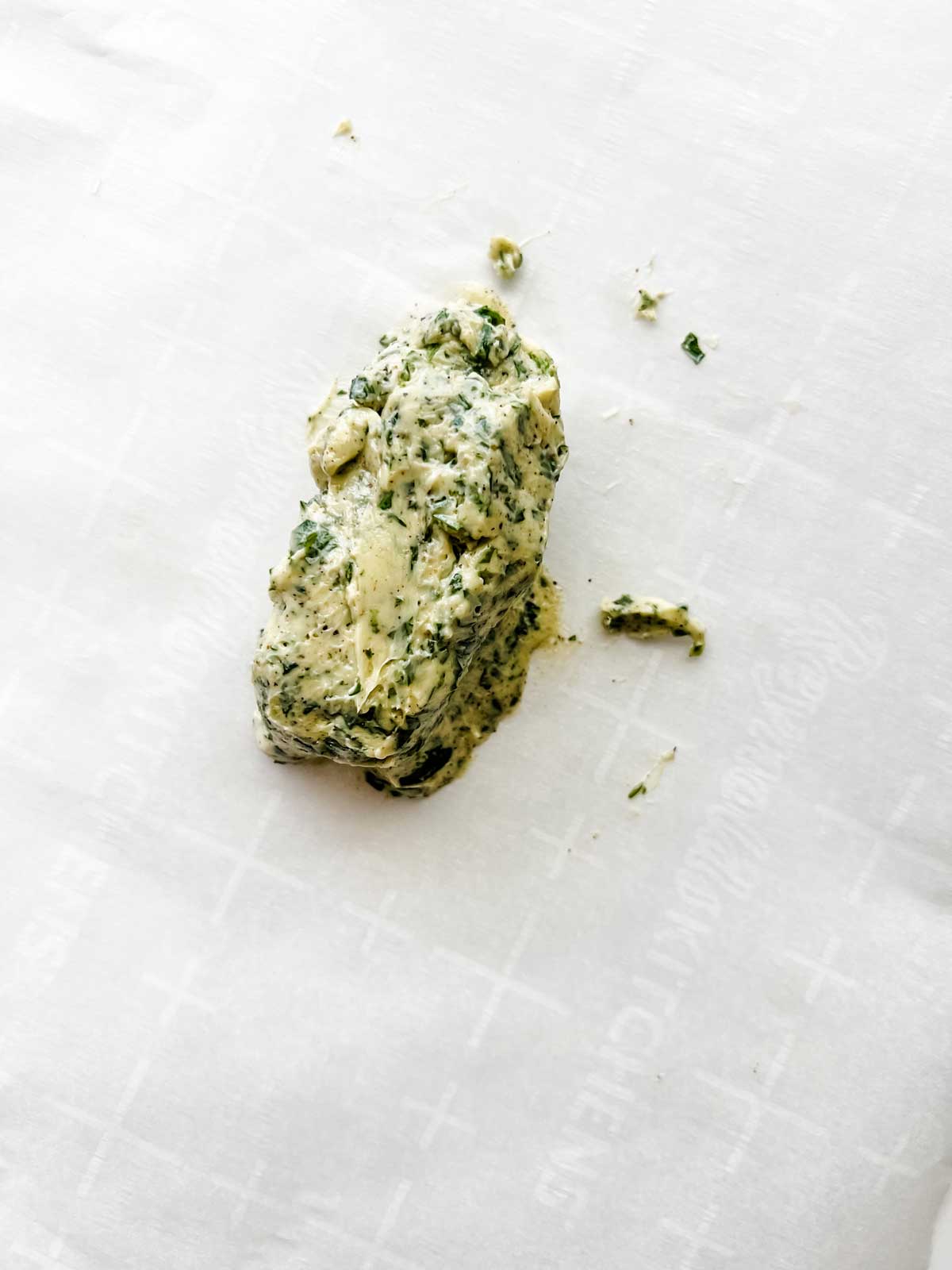 Photo of a herb butter on a sheet of parchment paper.
