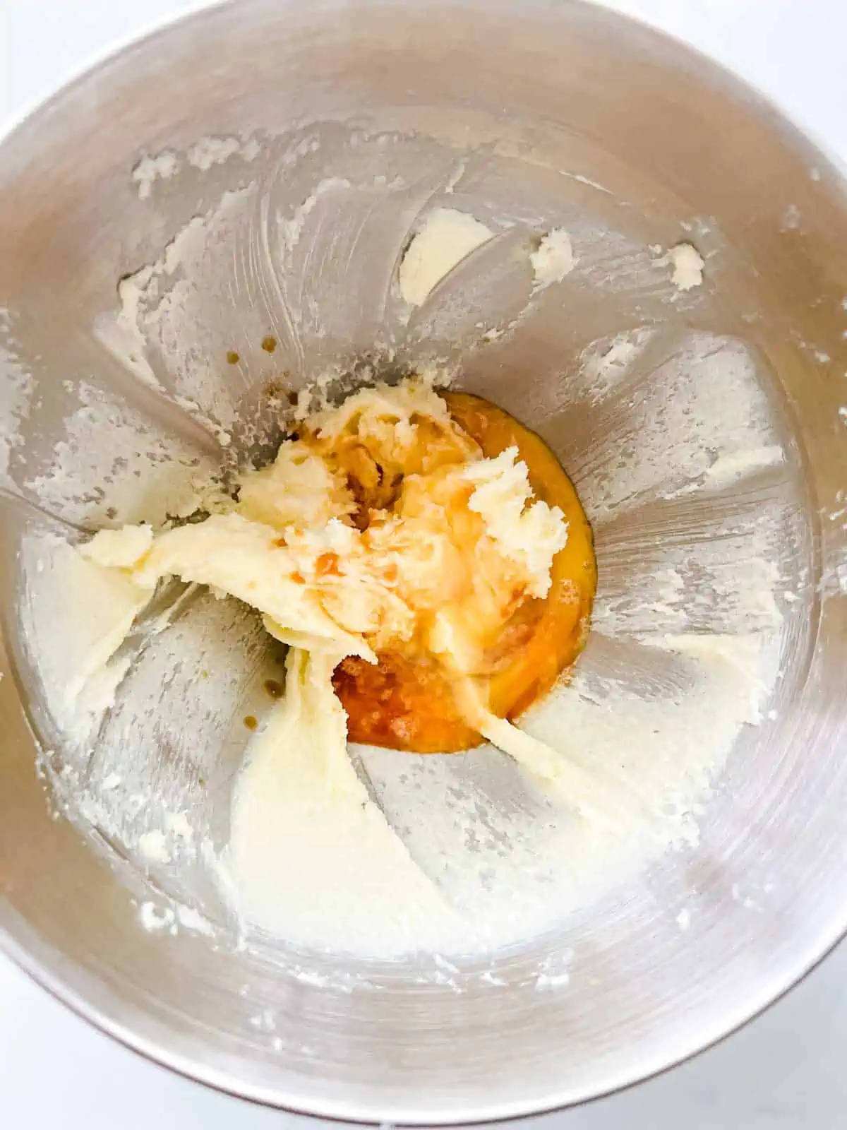 Photo of vanilla and egg being added to creamed butter and sugar.