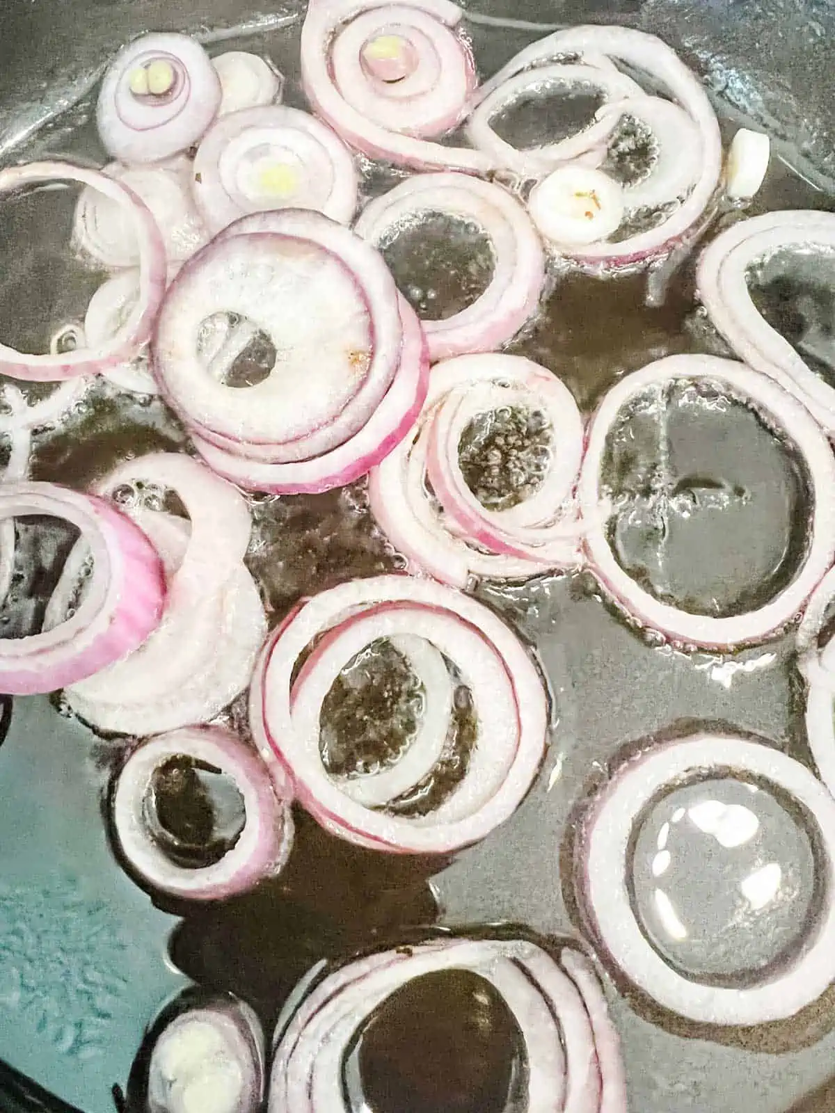 Photo of sliced onions cooking on a griddle.