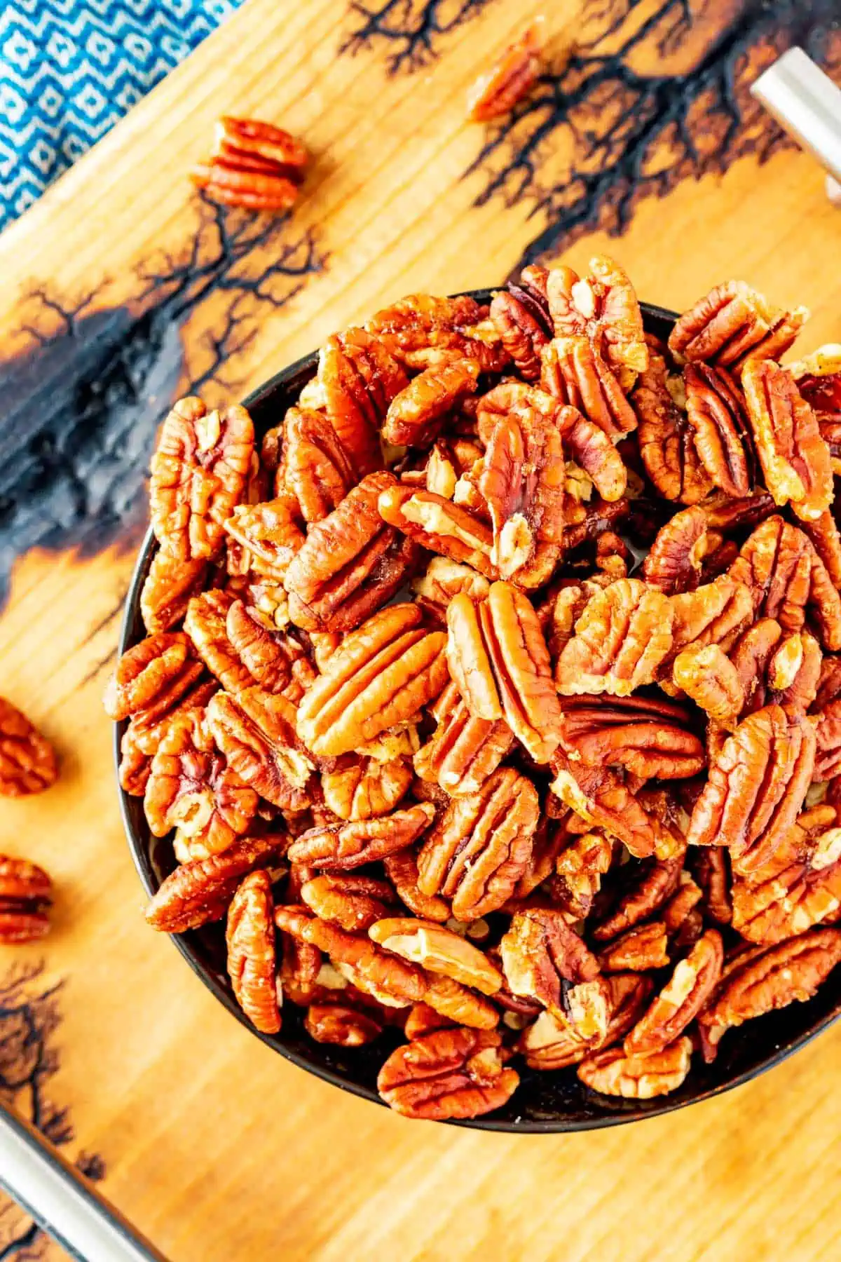 Overhead photo of a bowl of pecans on a rustic board.
