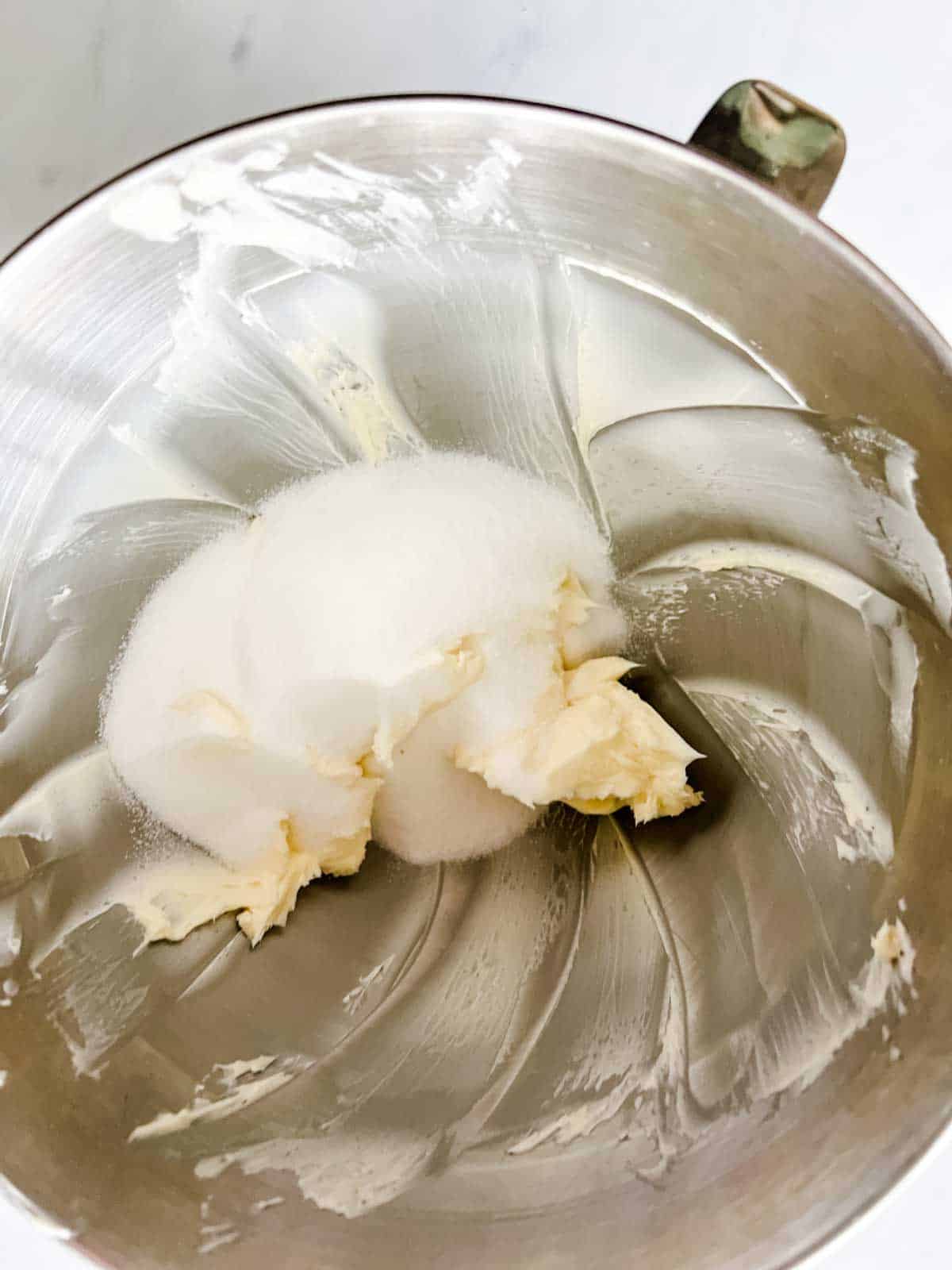 Photo of butter and sugar in the bowl of a stand mixer.
