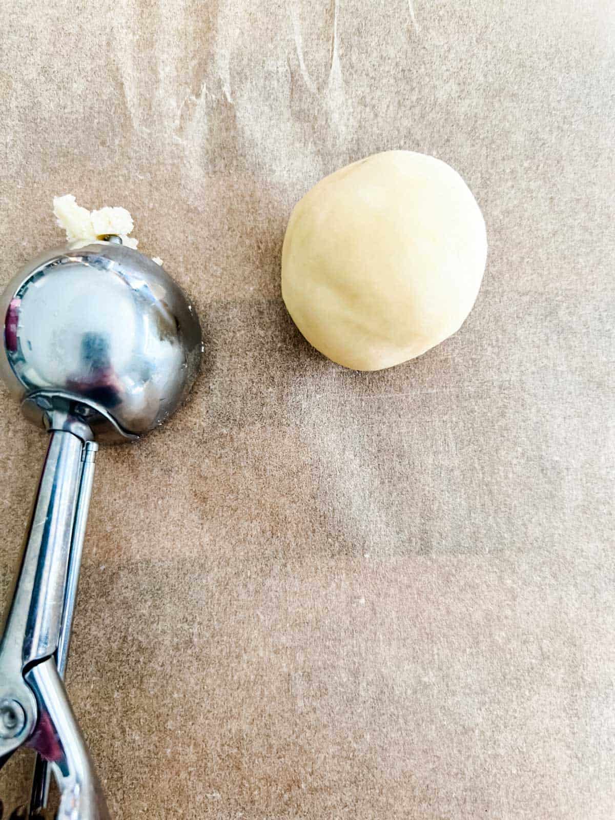 Photo of a cookie scoop and ball of cookie dough.