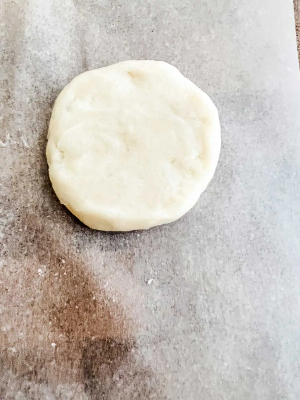 Photo of a raw sugar cookie that has been pressed flat.