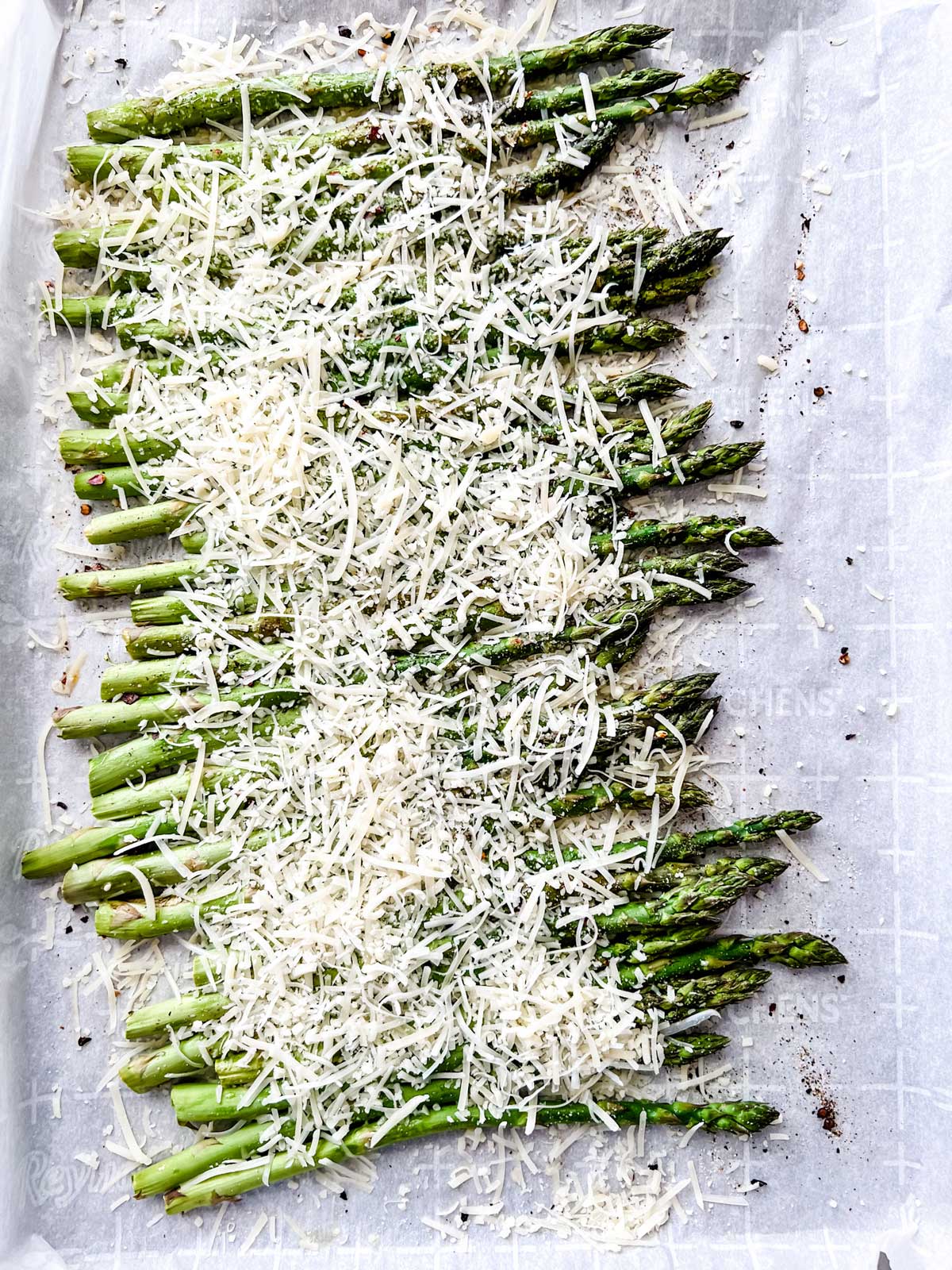 Partially cooked asparagus with parmesan sprinkled on top of it.