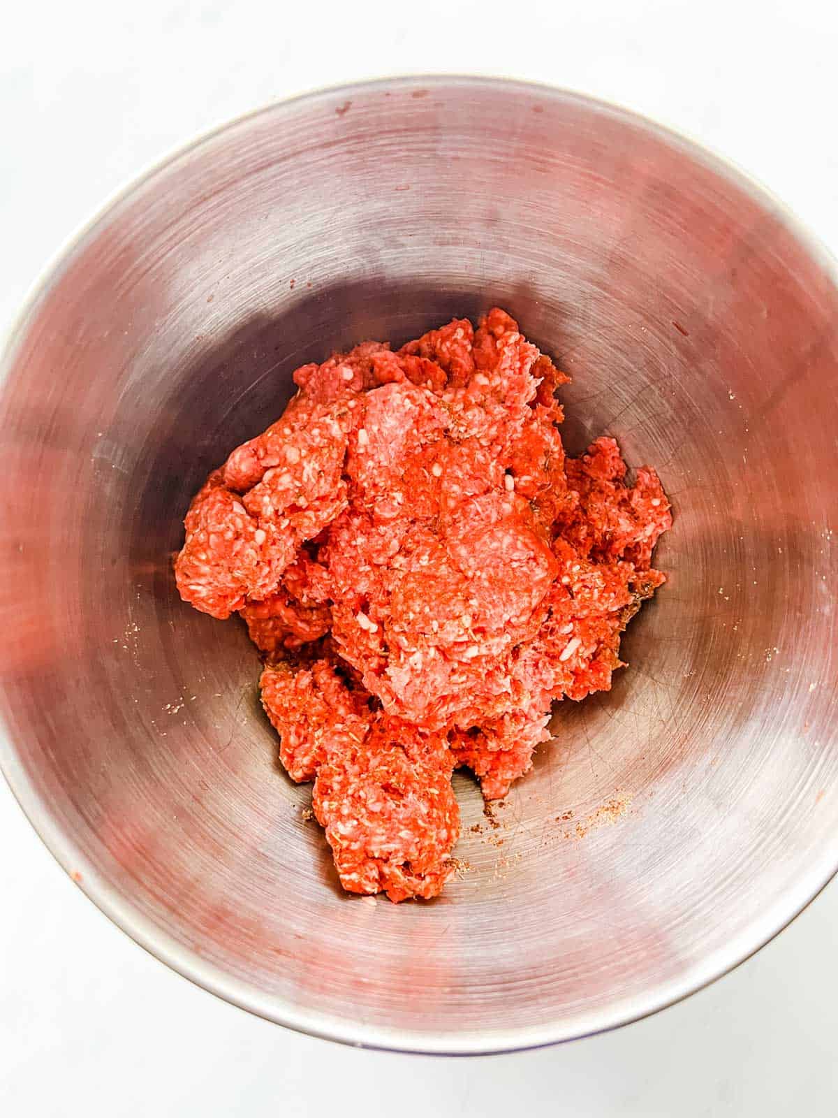 Ground beef and sausage seasonings that have been mixed together in a bowl. 