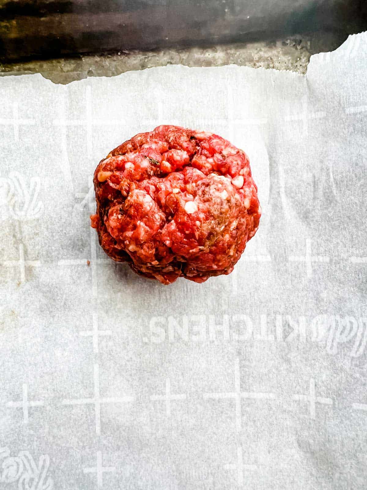 Ball of meat on a piece of parchment paper.