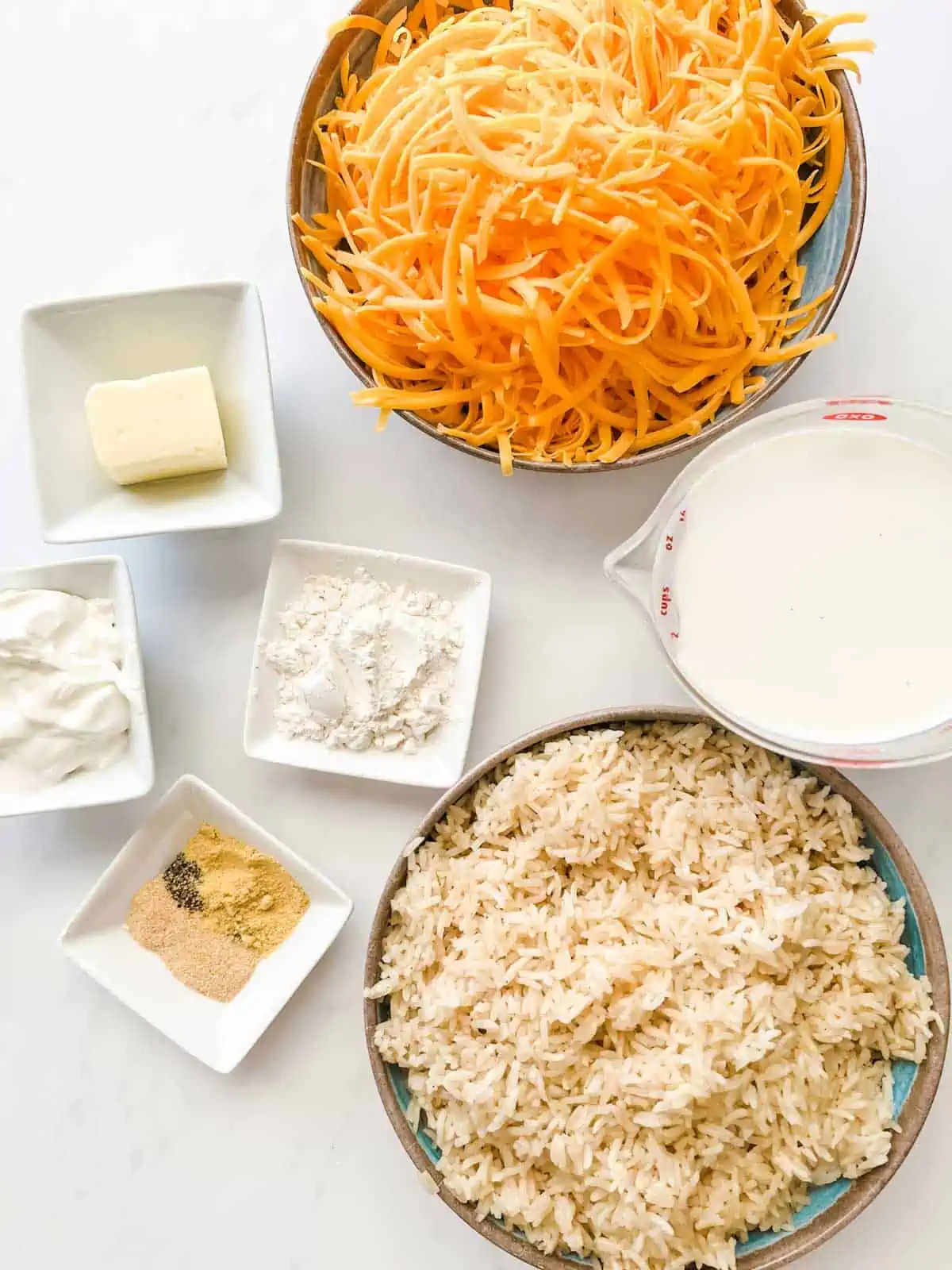 Overhead photo of prep containers with shredded cheese, rice, milk, flour, butter, sour cream and seasonings.