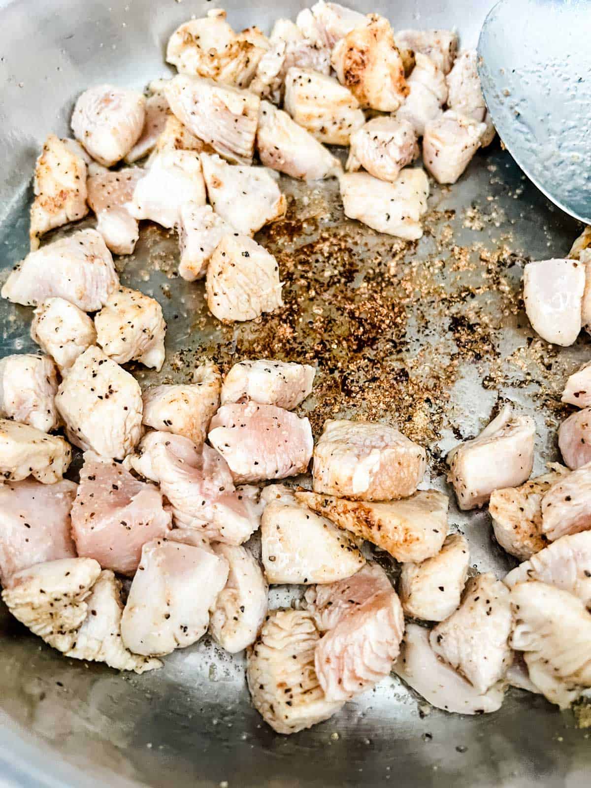 Photo of seasoned cubed chicken cooking in a skillet.