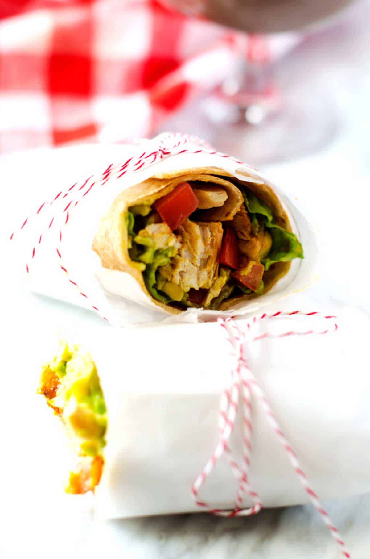 Photo of a guacamole wrap in parchment tied with red and white string.