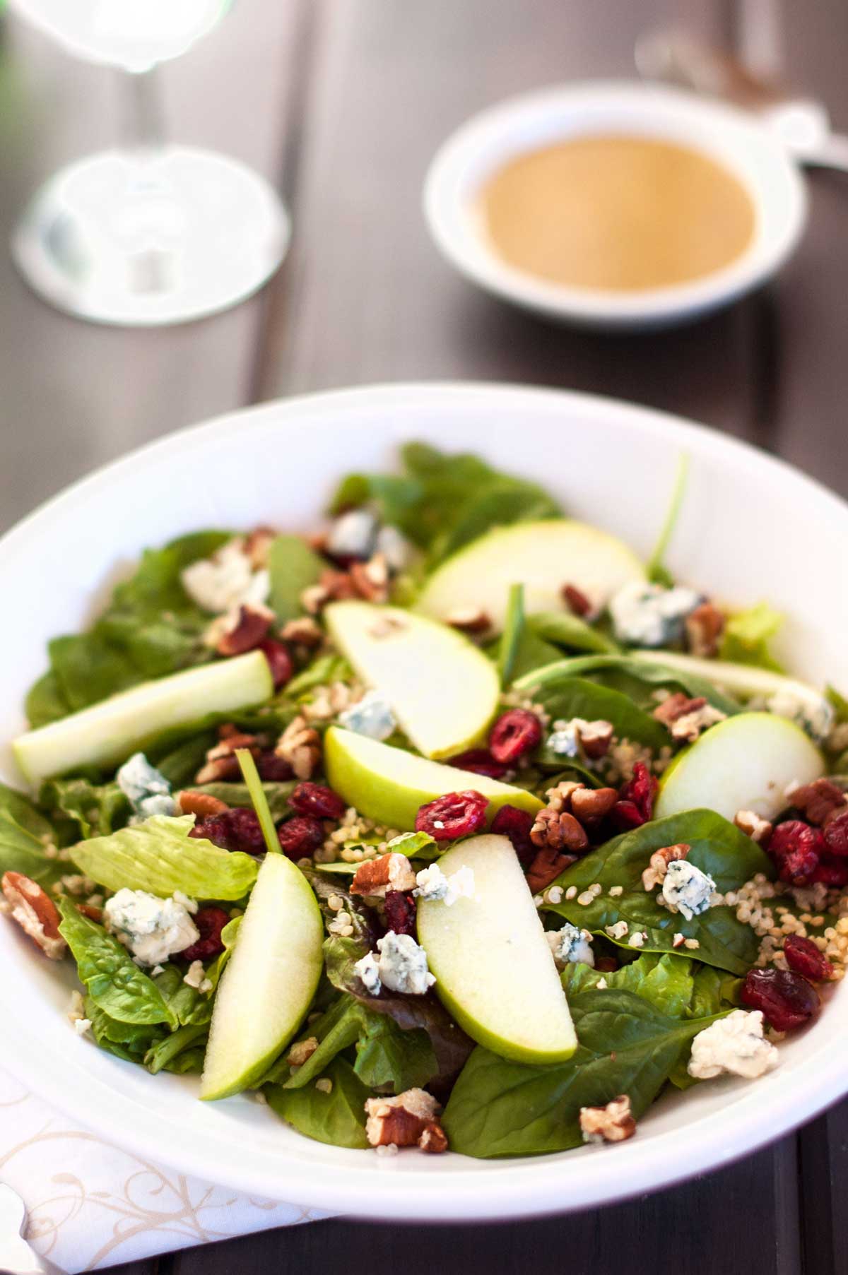 Photo of a white shallow bowl with cranberry apple quinoa salad.