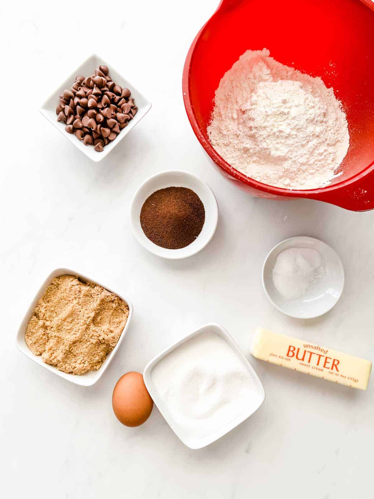 Overhead photo of flour, salt, baking powder, chocolate chips, espresso powder, brown sugar, egg, white sugar, and butter.