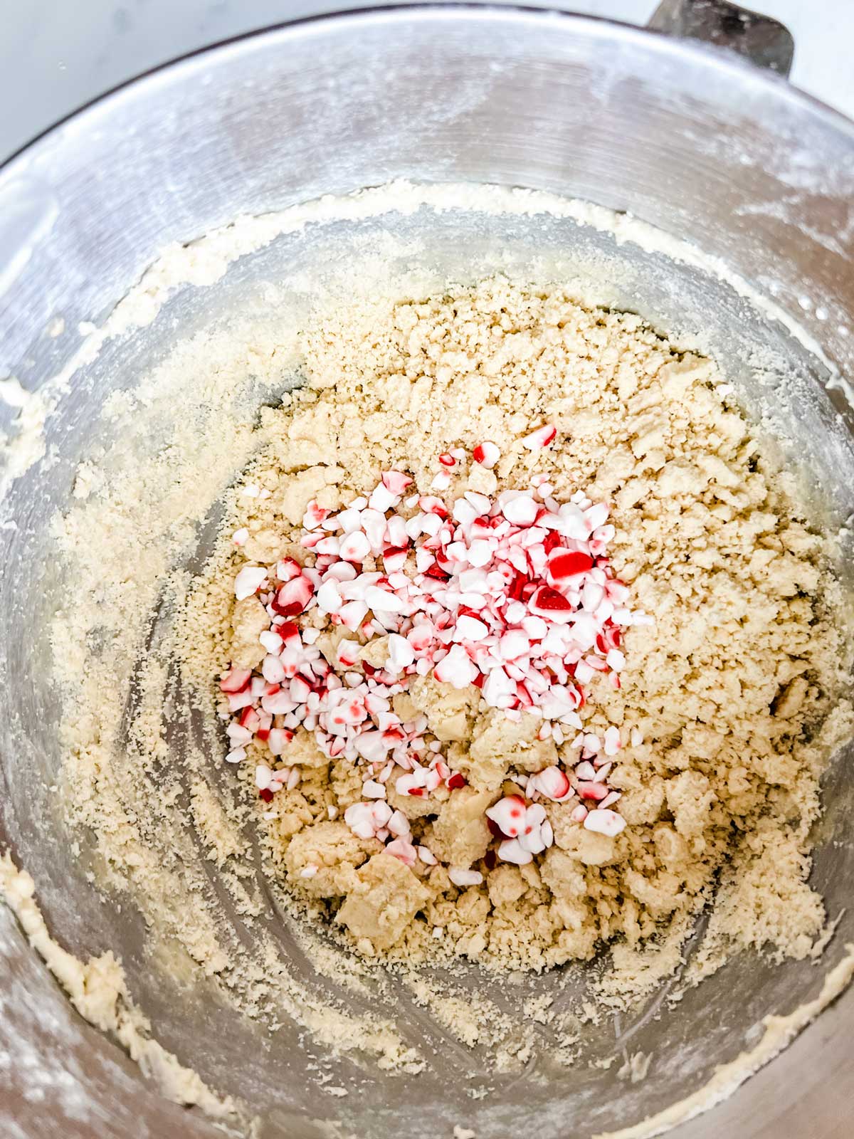 Snowball cookie dough that has just had crushed peppermint added to it.