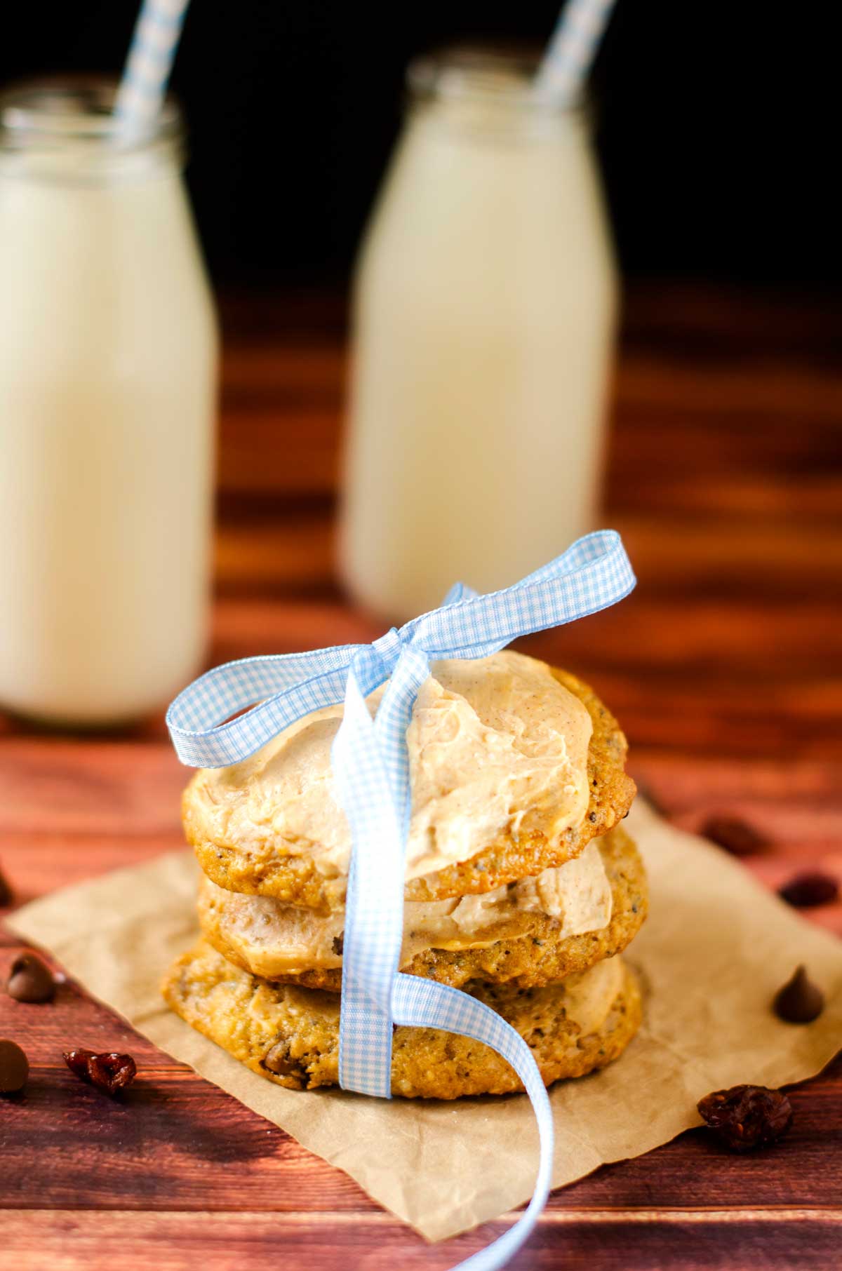 Photo of healthy breakfast cookies stacked and tied together with a ribbon with two milks behind them.