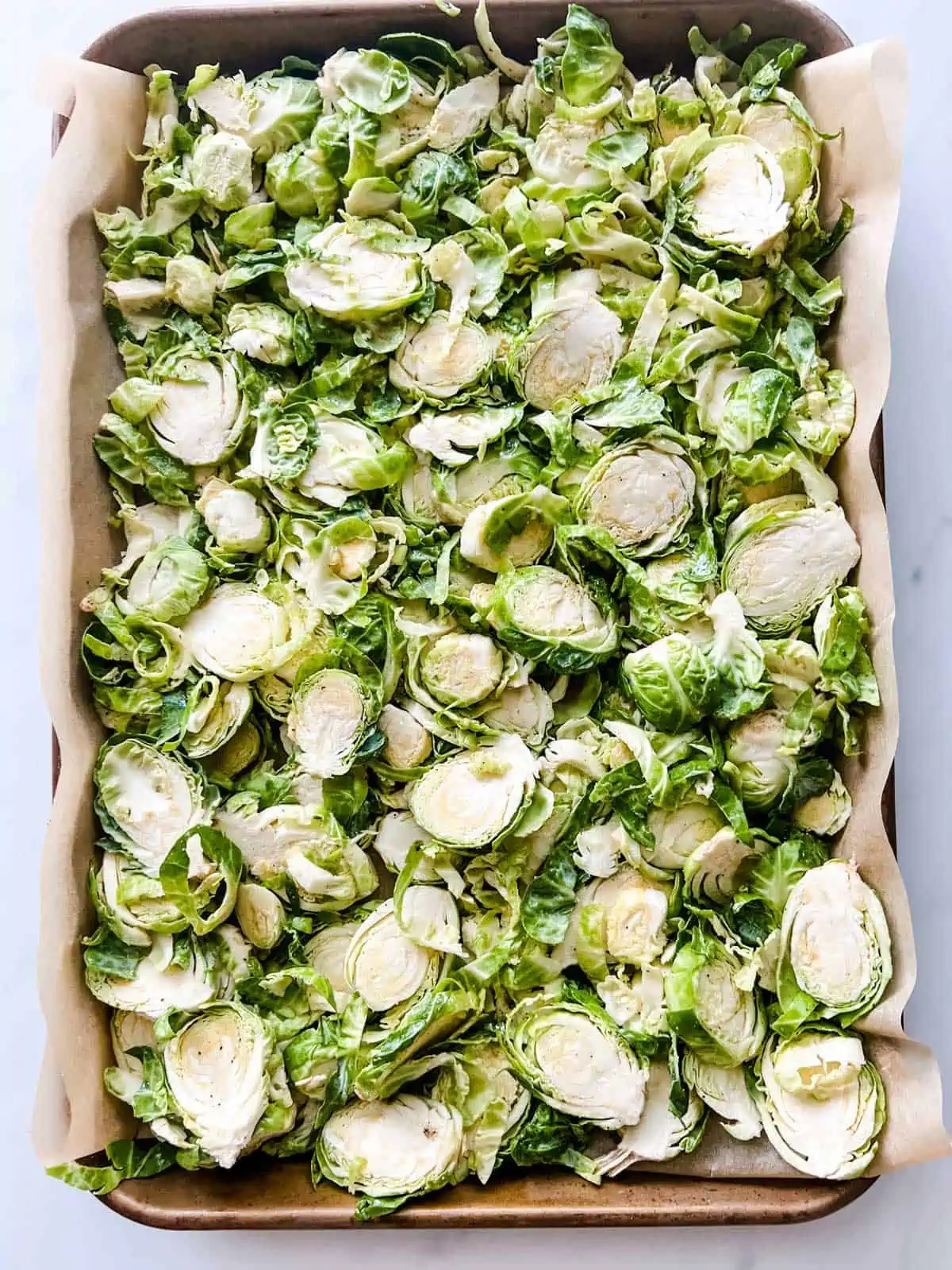 Photo of shaved brussels sprouts on a parchment lined baking sheet.