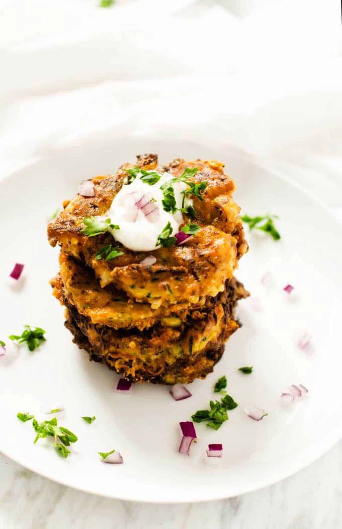Photo of zucchini pancakes on a white plate.