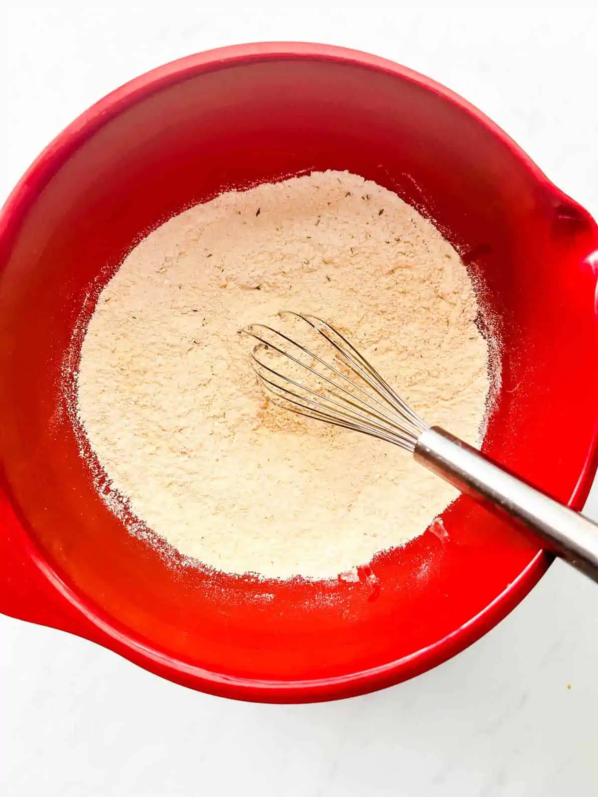 Photo of cornmeal, flour, sugar, baking powder, baking soda, salt, and thyme whisked together in a bowl.