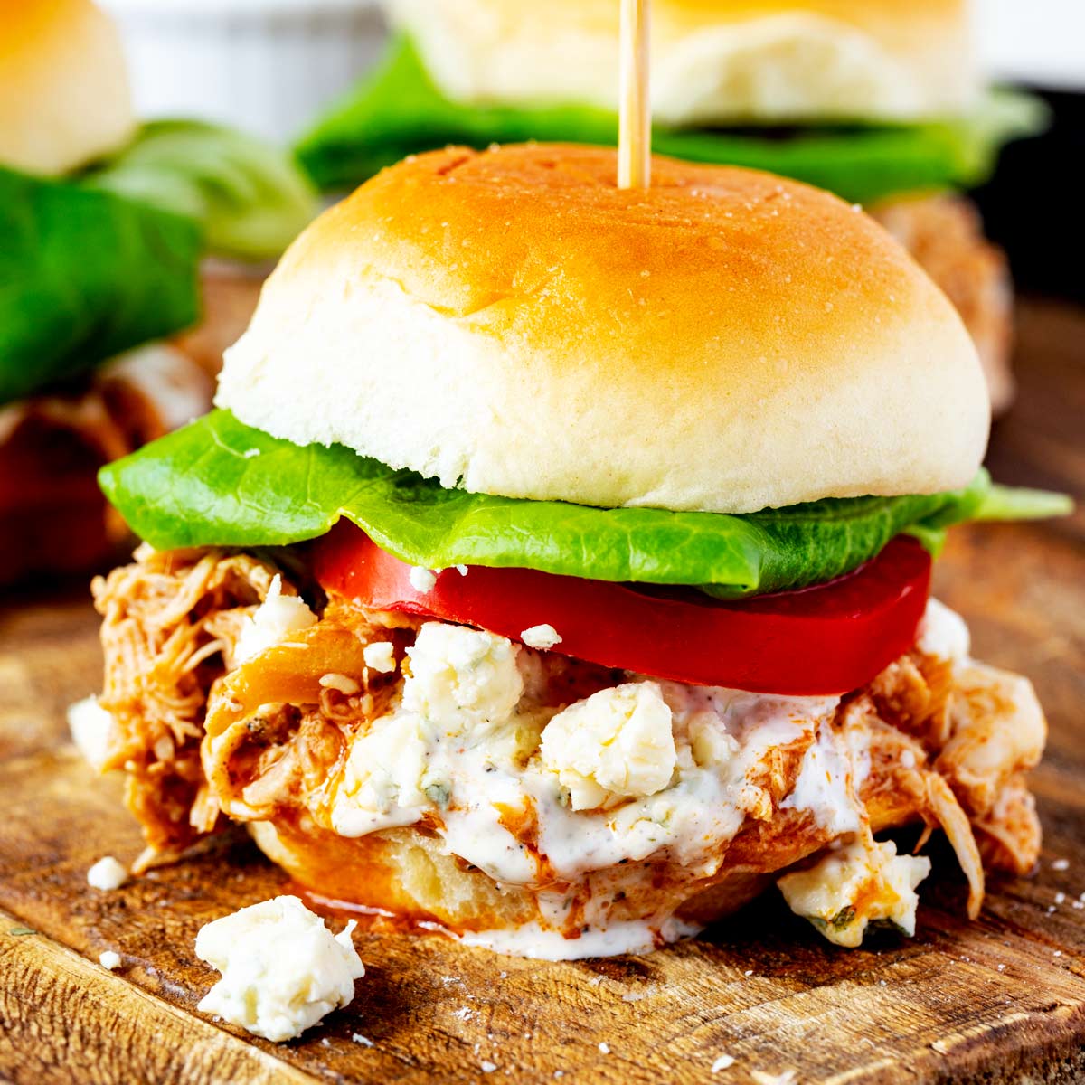Close up side photo of a buffalo chicken slider on a wooden cutting board.