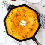 Square photo of a cast iron skillet with cornbread in it.
