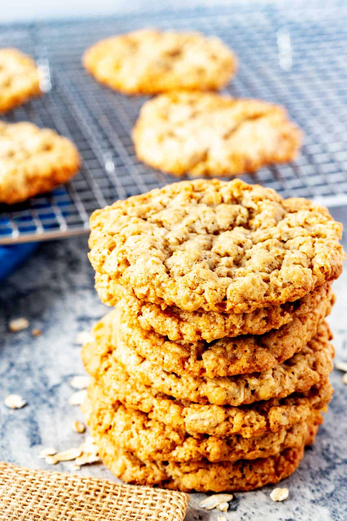 Photo of a stack of oatmeal cookies sitting in front of more cookies on a cooling rack.