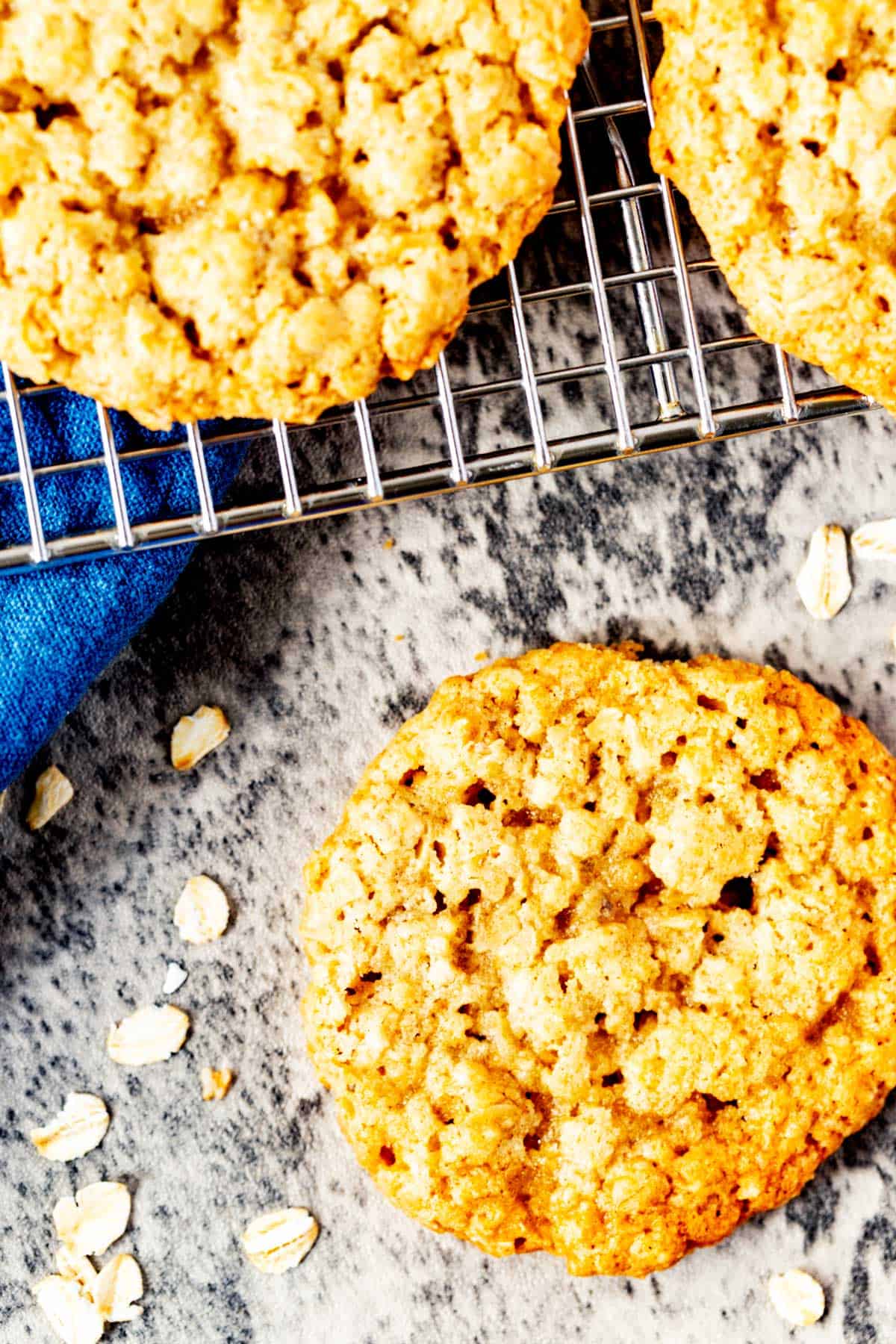 Overhead close up photo of an oatmeal cookie sitting in front of a cooling rack of cookies.