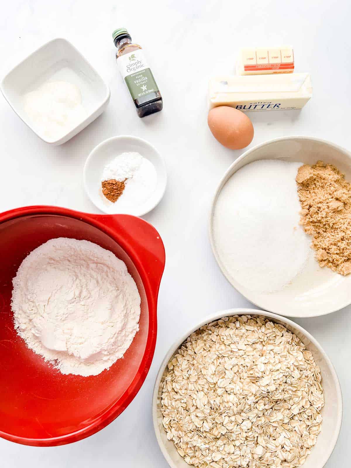 Overhead photo of flour, butter, sour cream, sugars, oats, egg, butter, vanilla, baking powder, baking soda, and cinnamon.