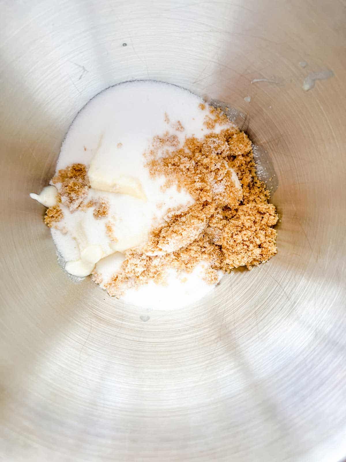 Photo of white sugar, brown sugar, and butter in the bowl of a stand mixer.